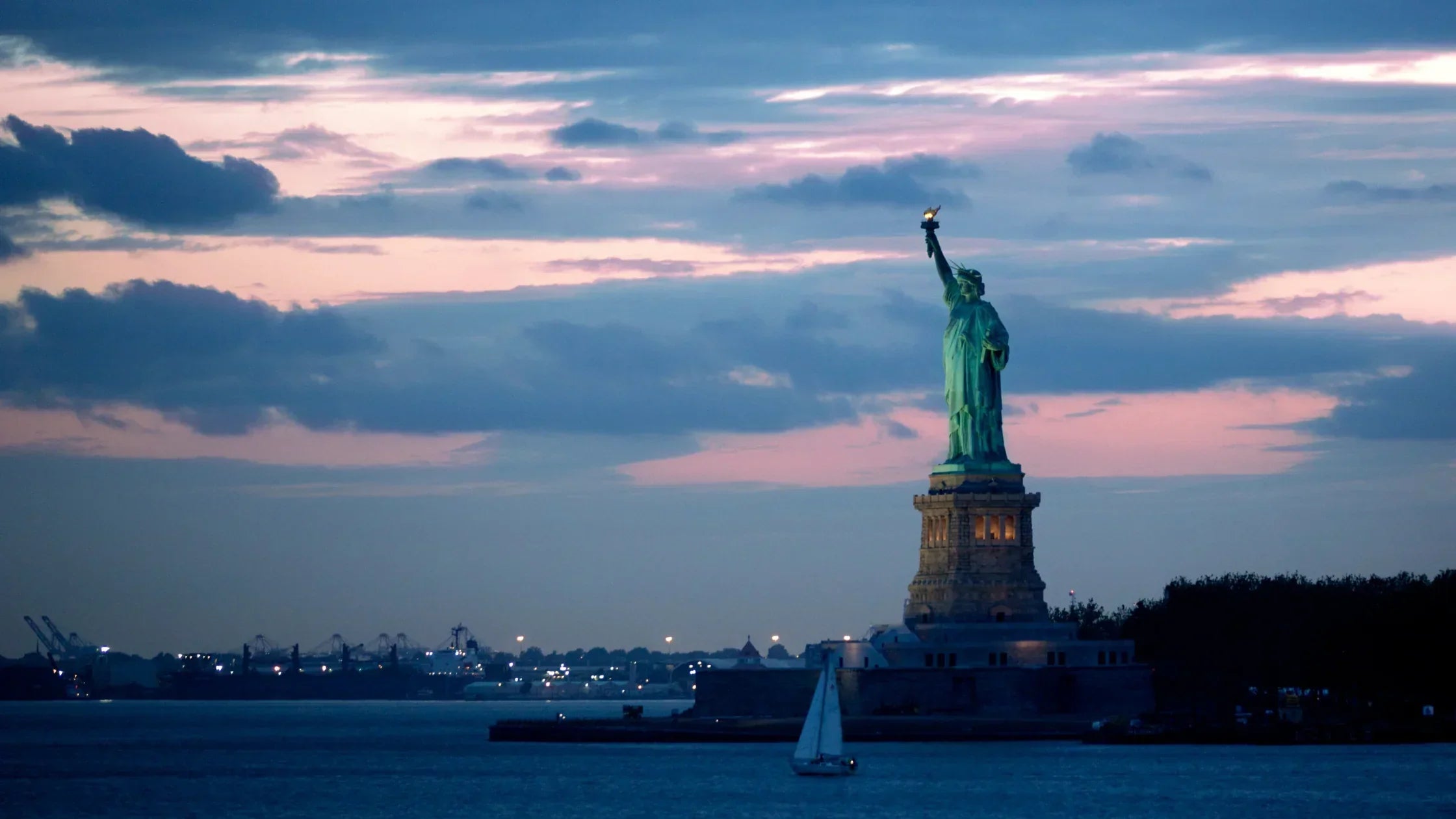 Statue of Liberty during sunset on a cloudy day.