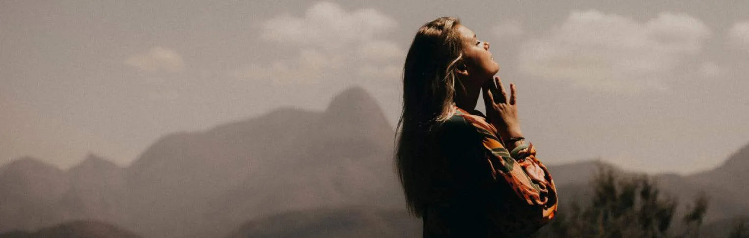 A profile of a woman looking off into the distance with mountains in the background.