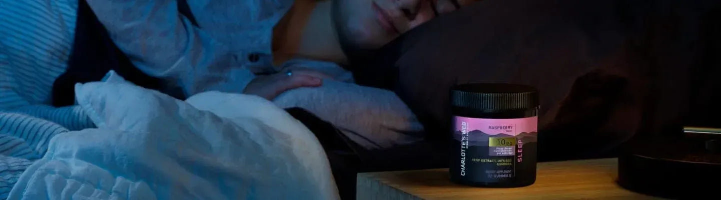 A jar of Charlotte's Web Sleep Gummy on a person's nightstand.