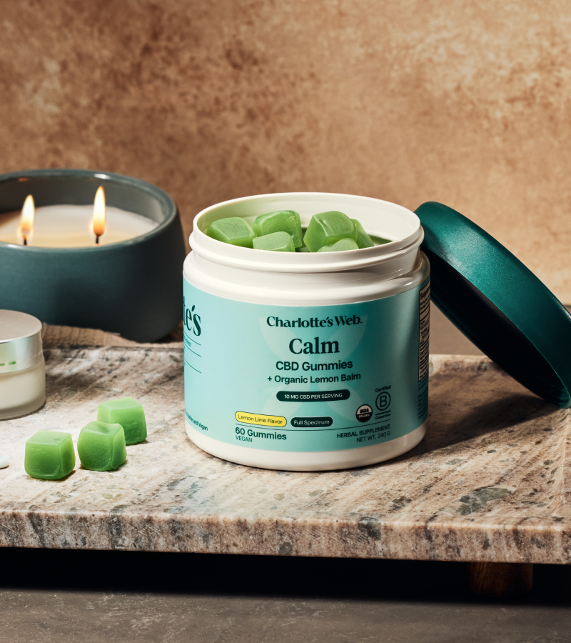 Gummies product on a wooden tray with green leaves and a neutral background