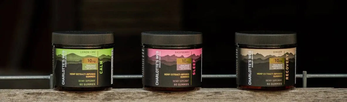 Three jars of Charlotte's Web Gummies on wooden shelf.