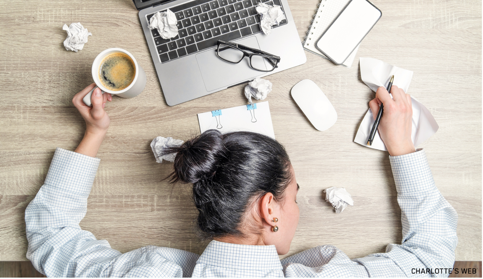 A person taking a nap at their desk, holding an XL cup of coffee, in need of help balancing sleep and energy levels. 