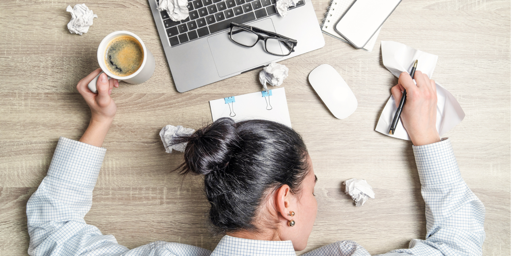 A person taking a nap at their desk, holding an XL cup of coffee, in need of help balancing sleep and energy levels. 