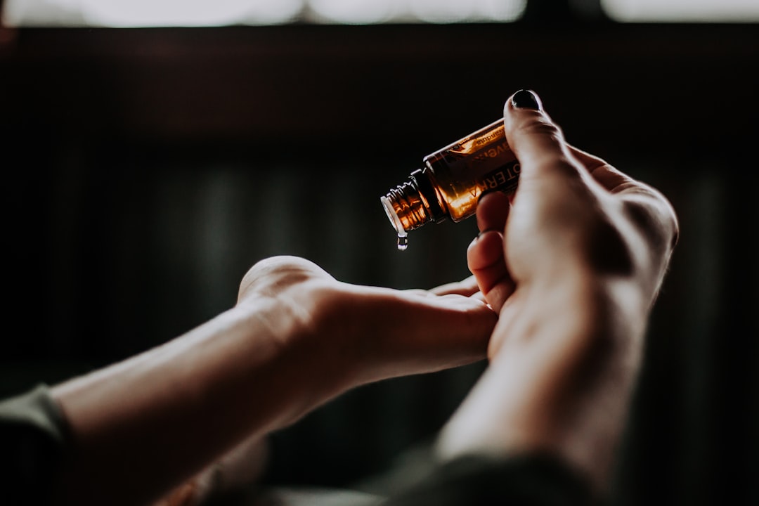 Person applying essential oil drops to hand