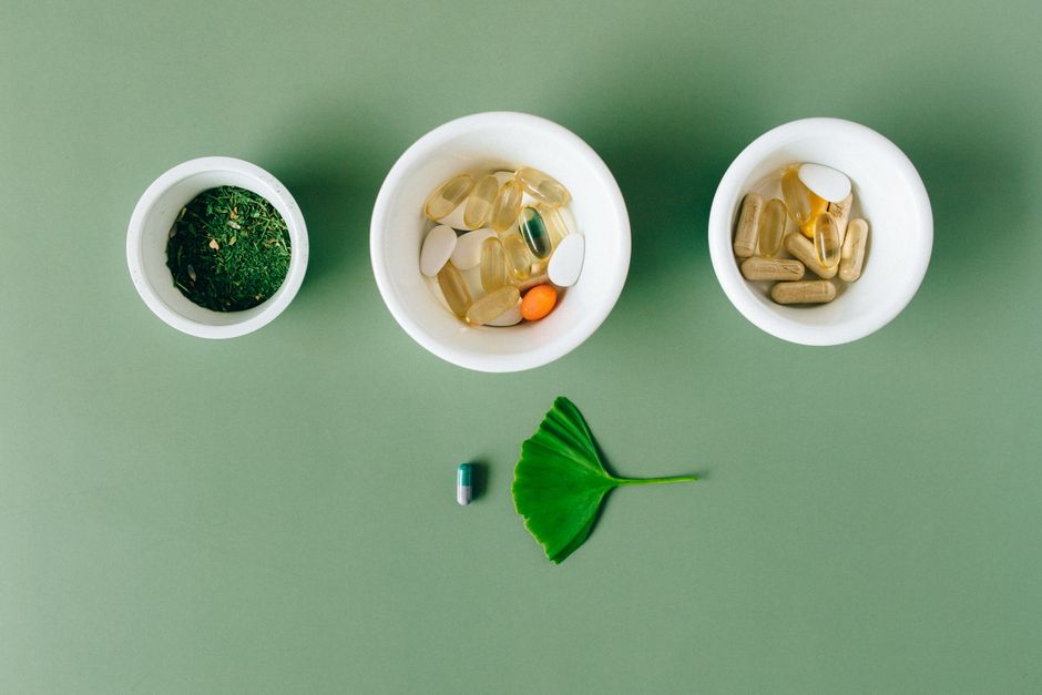 Bowls of herbal supplements capsules vitamins and green leaf