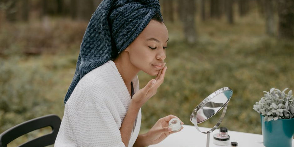 Woman applying face cream at outdoor table