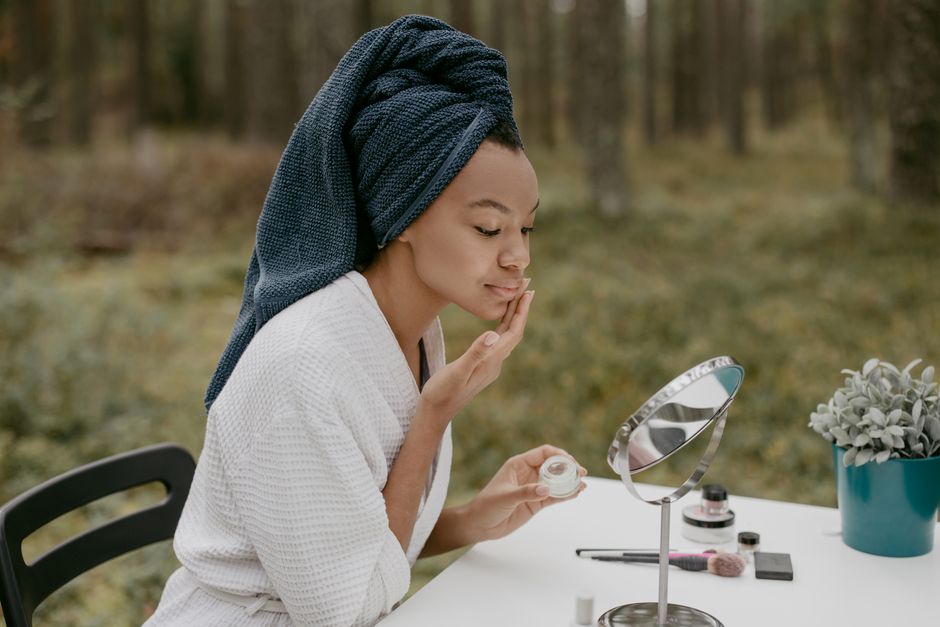 Woman applying face cream at outdoor table