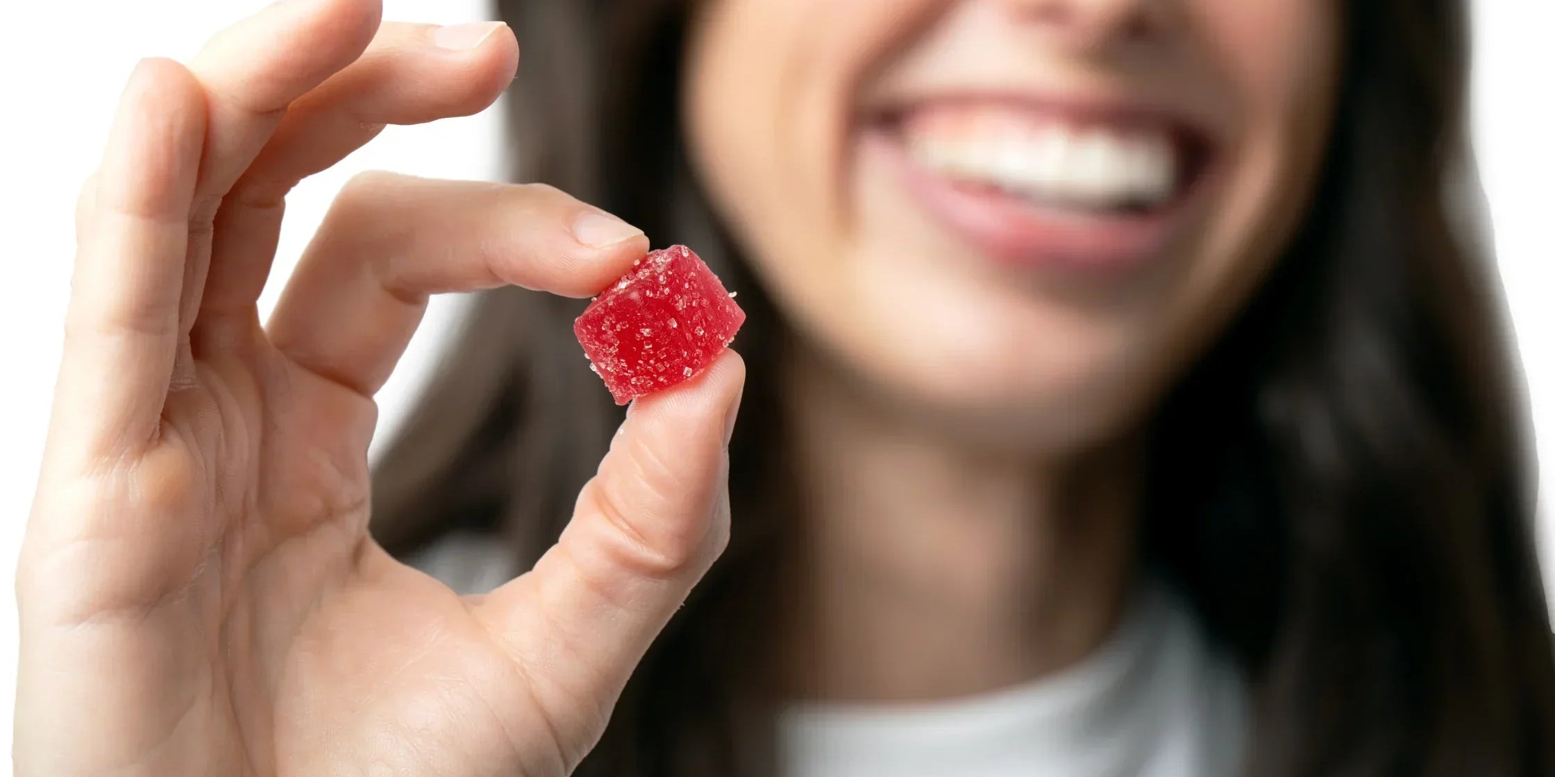 Closeup of a woman holding out a Charlotte's Web Brightside gummy.