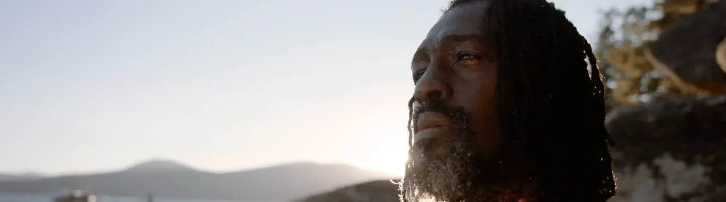 Man looking off in the distance with mountains in the background.