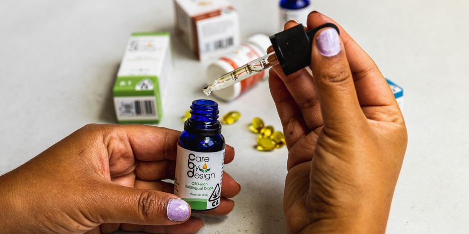 Hands holding CBD oil dropper and bottle