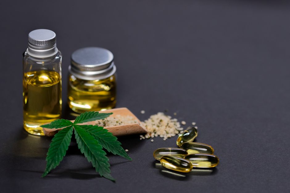 CBD oil bottles capsules hemp leaf and seeds