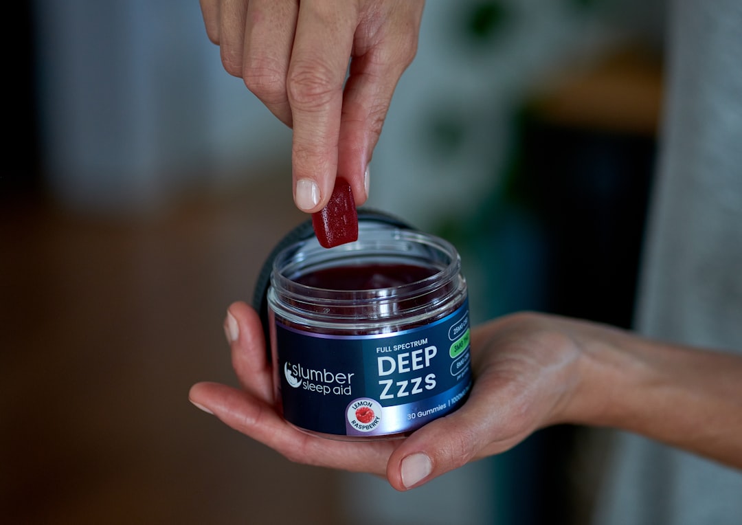 Hand taking gummy from Deep Zzzs sleep aid jar