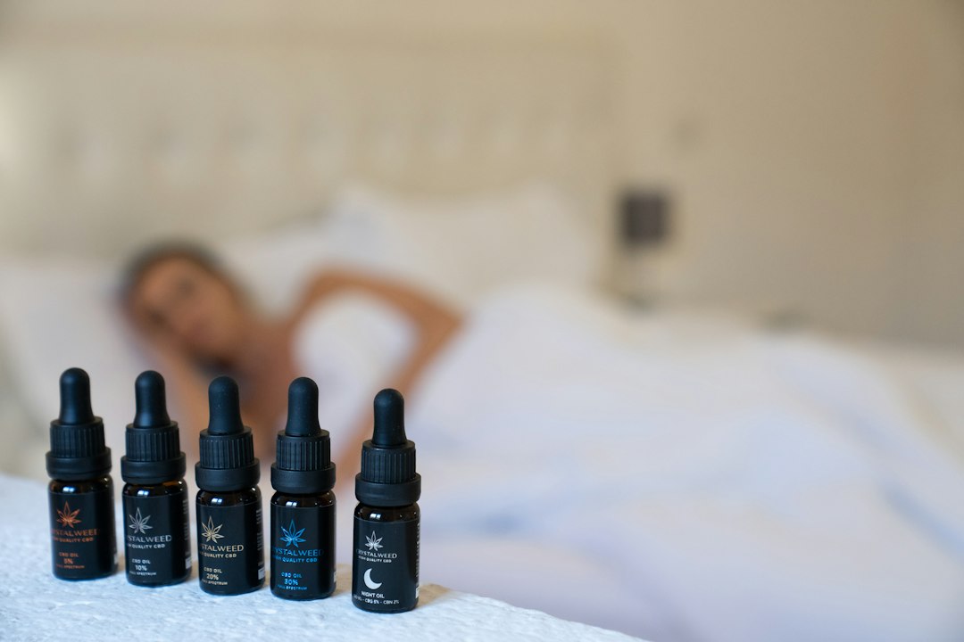 Five CBD oil bottles near a bed