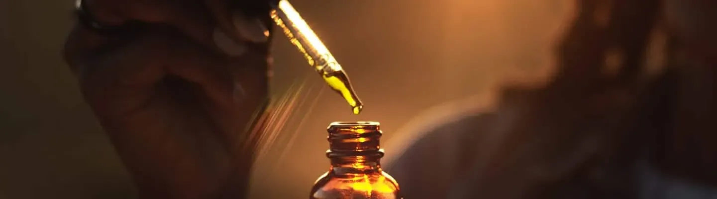 Dropper dispensing CBD oil into amber bottle for wellness