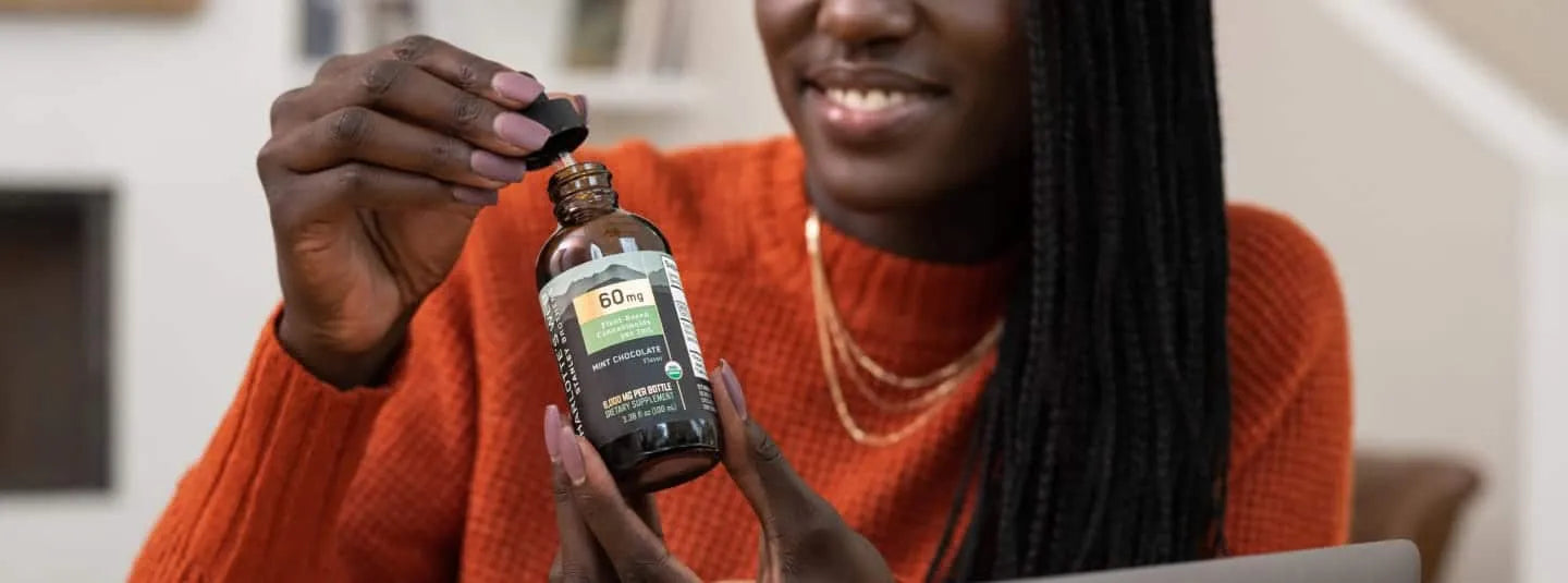 A woman opening a bottle of Charlotte's Web CBD Oil.