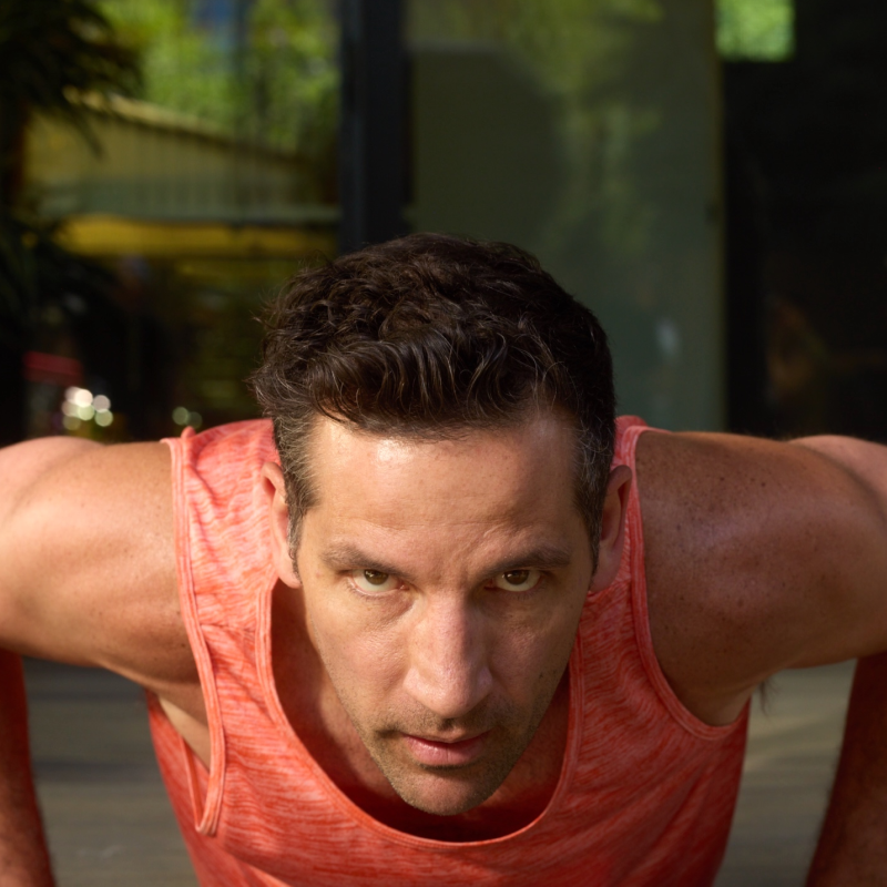 Man in a red tank top doing push-ups outdoors