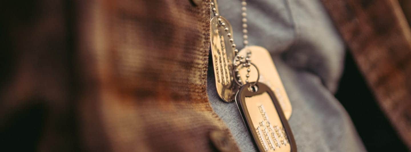 Close-up of a person wearing a necklace with dog tags.