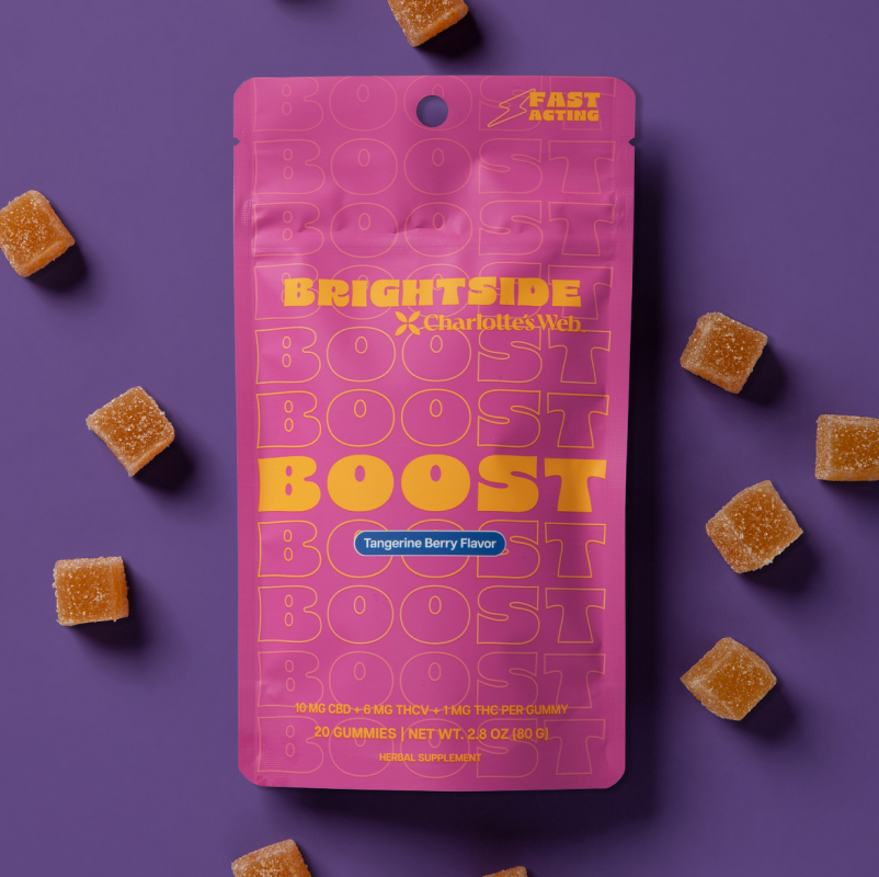 Pink package of Charlotte's Web Boost with orange gummies on a purple background