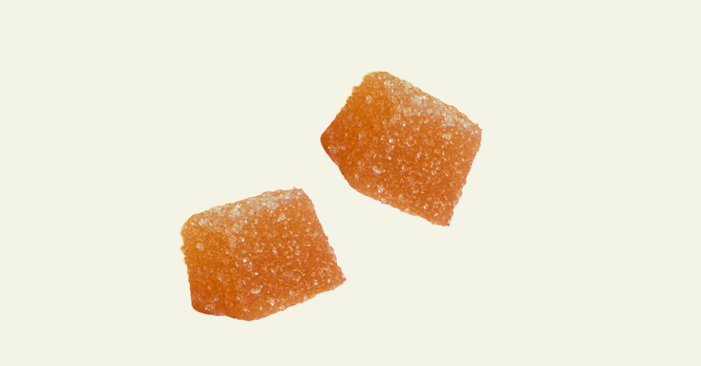 Two orange sugar coated gummy squares on beige background