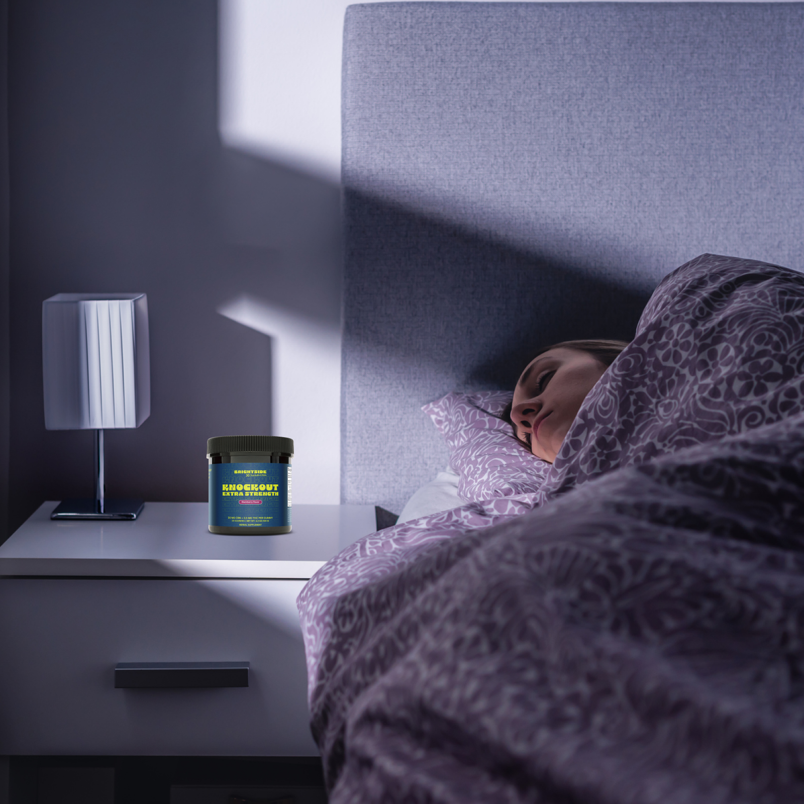 Product Image for Person lying in bed with a supplement container on a nightstand next to a lamp.