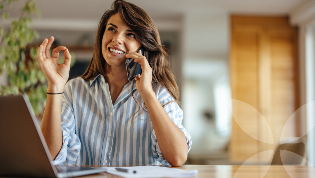 Woman on a phone call with a laptop at a desk in a home office setting