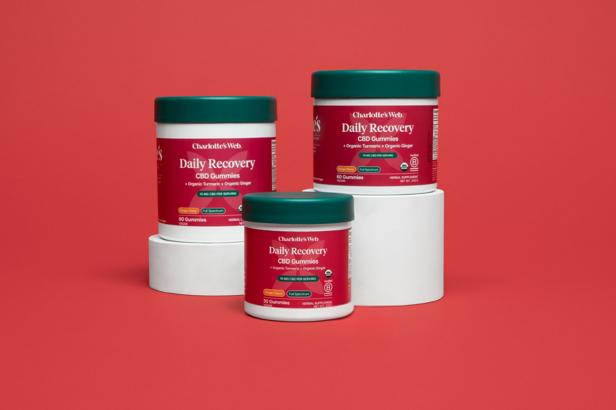 Three containers of Charlotte's Web Daily Recovery CBD Gummies on a red background