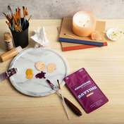 Product Image for Artistic setup with paintbrushes, a candle, and a Charlotte's Web Brightside Daytime package on a wooden table.