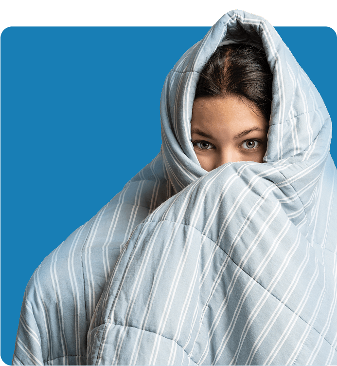 Person wrapped in a large quilt against a blue background