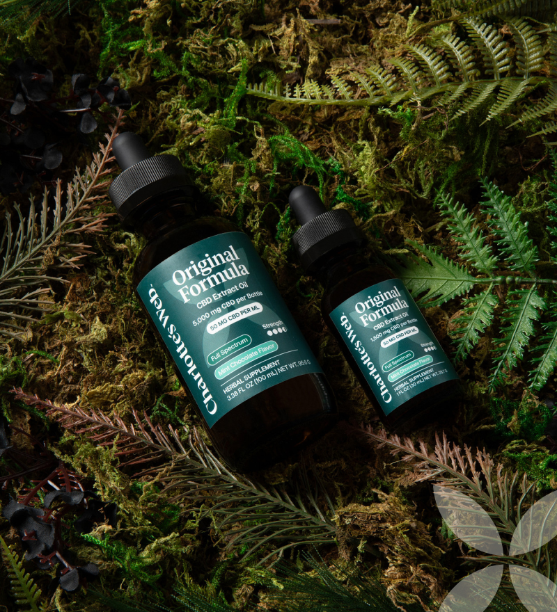 Two bottles of Original Formula CBD Extracts on a background of green foliage.