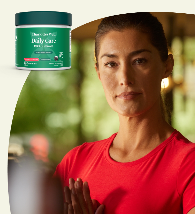 Woman in a red shirt with a jar of Charlotte's Web Daily Care CBD Gummies on a white background