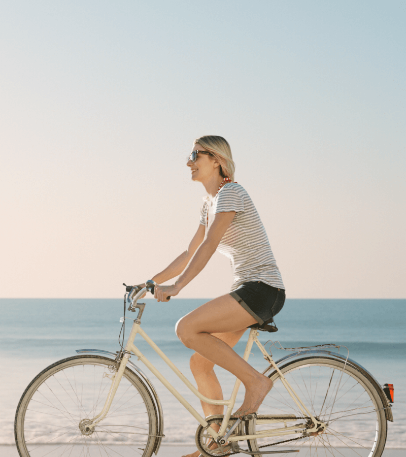 Woman riding a bicycle on a beach with a clear sky